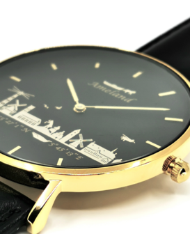 Detail van de Ameland skyline op een zwarte wijzerplaat van een 40mm goudkleurig horloge met lederen band
