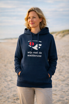 Anne op het strand met een navyblauwe &lsquo;wijs met de waddenzee&rsquo; hoodie, gefotografeerd aan de Waddenzee met rust