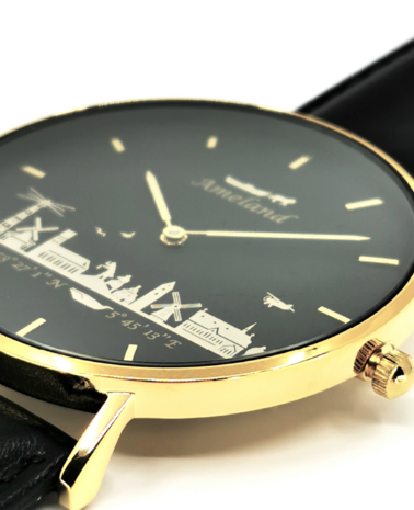 Detail van de Ameland skyline op een zwarte wijzerplaat van een 40mm goudkleurig horloge met lederen band
