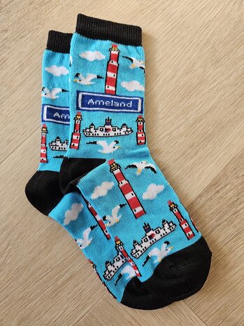 Lichtblauwe Ameland kindersokken met illustraties van de rood-witte vuurtoren, witte meeuwen en de veerboot